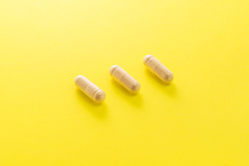 Herbal medical capsule on a yellow