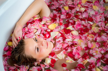 Obraz na płótnie Canvas girl in the bathroom with rose petals, close up portrait