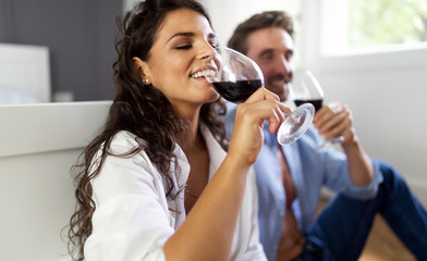 Beautiful couple is drinking wine, talking and smiling while spending time together at home