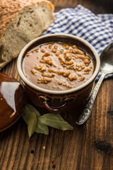 tripe stew sauce in brown ceramic pot on a wood table 
