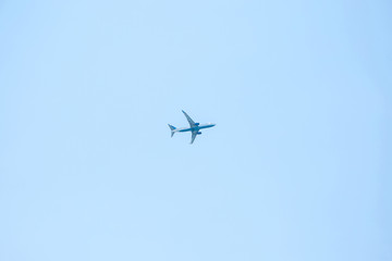 An airplane or a plane flies against a blue sky in a minimalist style.