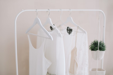 White dresses on a hanger. Minimalism concept. Set of women wedding dresses on a wooden hangers, fashion background, close up