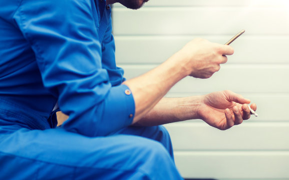 car service, repair, maintenance and people concept - auto mechanic smoking cigarette at workshop - Powered by Adobe