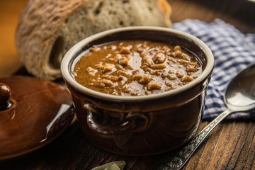 tripe stew sauce in brown ceramic pot on a wood table 
