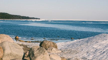 Snow pile, hill. Large snow drift isolated on a blue sky background,  outdoor view of ice blocks at frozen finland lake in winter