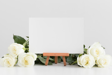 White card mockup with roses on a white table.