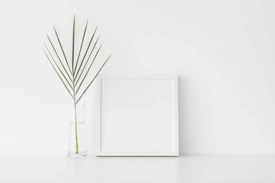 White square frame mockup with palm leaf in a glass vase.