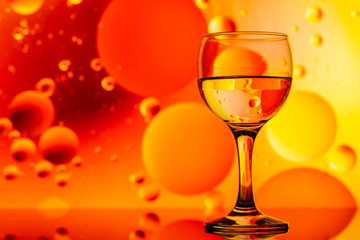 transparent glasses with water and oily drops on colorful background 