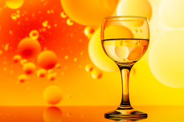 transparent glasses with water and oily drops on colorful background 