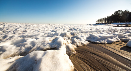 Snow pile, hill. Large snow drift isolated on a blue sky background,  outdoor view of ice blocks at frozen finland lake in winter