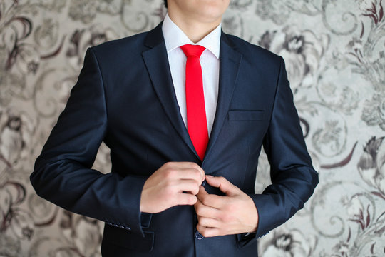 Businessman in black suit and a red tie. Smart casual outfit. Man getting ready for work. groom in a jacket, the groom fastens his jacket, The morning of the groom, bridegroom's fees