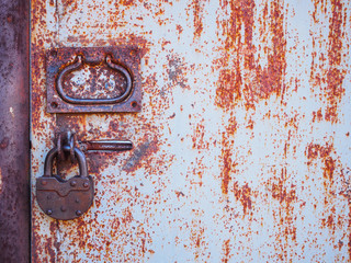 The texture of the door and the lock of the old rusty red metal