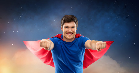 super power and people concept - happy young man in red superhero cape over starry night sky...