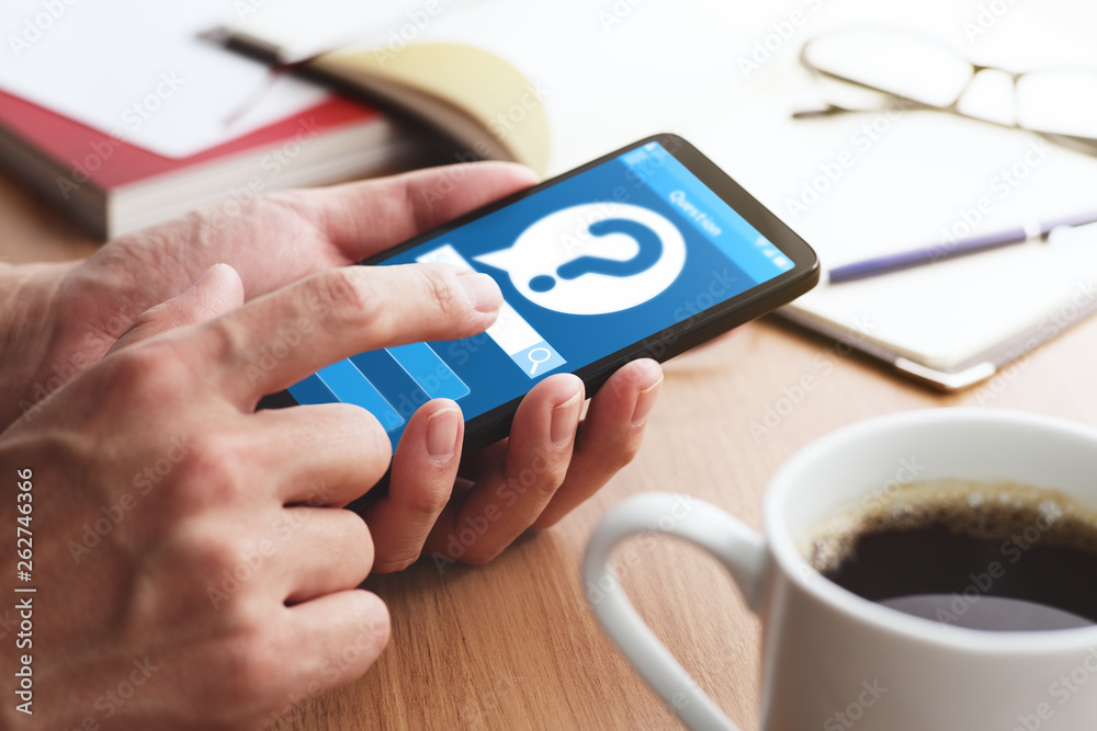 Poster question mark icon on smartphone screen.closeup of male hands touching smartphone screen at table.
