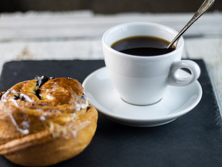 Sweet buns and cup of coffee on a dark stone background