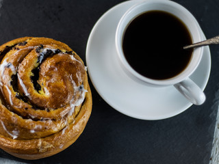 Sweet buns and cup of coffee on a dark stone background