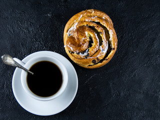 Sweet buns and a cup of coffee on a dark stone background
