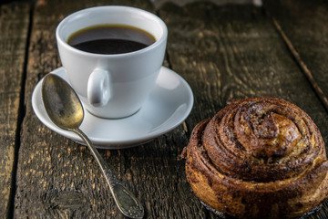 Cup of coffee and sweet buns on a rough wooden background