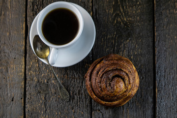 Cup of coffee and sweet buns on a rough wooden background
