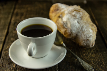 Cup of coffee and sweet buns on a rough wooden background