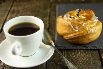 Cup of coffee and sweet buns on a rough wooden background