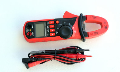 Device for measuring voltage in an electrical outlet with a multimeter on a white background. equipment, apparatus.