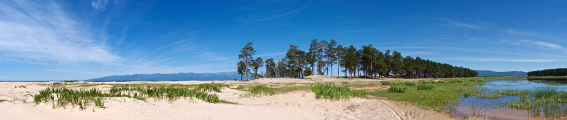 Fototapeta na wymiar Beautiful lakeshore panorama of white sand and pine forest on mountains background