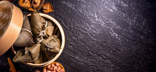 Close up, copy space, top view, flat lay. Famous asian chinese tasty handmade food in duan wu event, steamed rice dumplings shaped like pyramidal ingredient on black slate