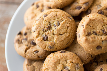 food, junk-food and eating concept - close up of oatmeal cookies with chocolate chips on plate