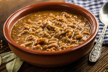 tripe stew sauce in brown ceramic pot on a wood table 