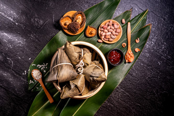Close up, copy space, top view, flat lay. Famous asian chinese tasty handmade food in duan wu event, steamed rice dumplings shaped like pyramidal ingredient on black slate