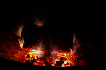 Lagerfeuer in der Nacht mit Flammen um großes Holzstück