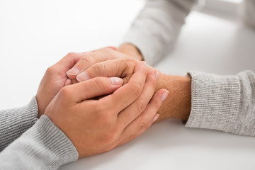 old age, family, care and support concept - close up of young woman holding senior man hands