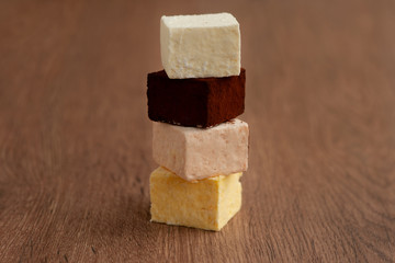 Souffle of different colors on a wooden background. Dessert in the form of souffle or candy. Truffle effect. Multicolored sweets closeup.