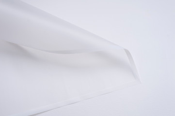 transparent paper corner with white edges on white background. floristics and packaging concept. white floral paper sheet