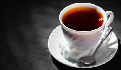 The white cup with black tea on Dark grey black slate background. Copy space.