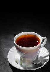 The white cup with black tea on Dark grey black slate background. Copy space.