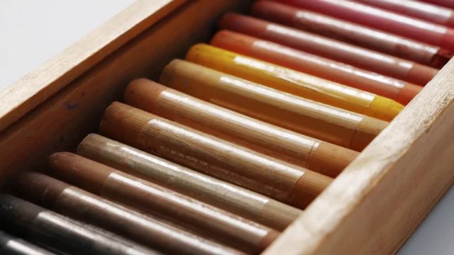 Close-up of the rotation of a set of pastel crayons. Pastel crayons paint special box. Accessories for painting with pastels. Concept school of art and drawing training. Soft focus.