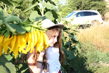 portrait of a beautiful girl in a straw hat with long hair in a sunflower field of sunflowers