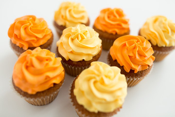 food, pastry and confectionery concept - cupcakes with buttercream frosting over white background