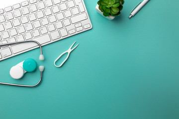 Stethoscope in doctors desk with keyboard, glasses and contact lenses