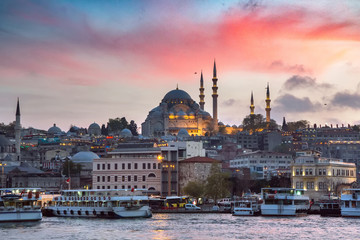 Naklejka premium Eminonu Pier on a sunset on Golden Horn with a view of the Historic Suleymaniye Mosque on Hill in Istanbul Old City, Turkey