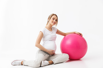 Fototapeta na wymiar Beautiful young pregnant yoga fitness woman posing isolated over white wall background make exercises with ball.