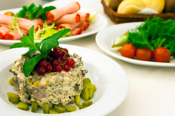 Russian salad with mushrooms and red currants, meat rolls and pickled vegetables on the holiday table