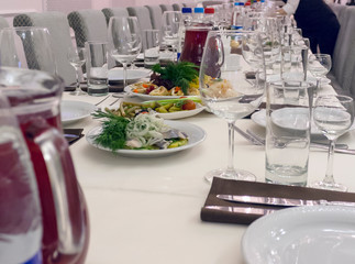 vegetable appetizers with spices on a set table, surrounded by glasses and drinks