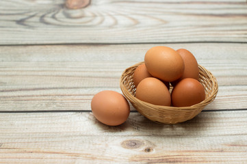  Raw chicken eggs in a wicker basket on a wooden background