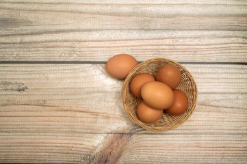 Raw chicken eggs in a wicker basket on a wooden background