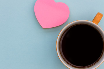Coffee cup and pink love heart top view on blue color minimal background