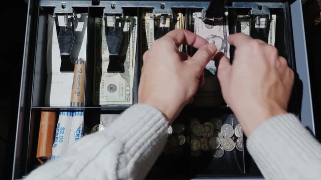 POV video: The cashier puts the money in the cash register and takes the change. Retail for cash US dollars