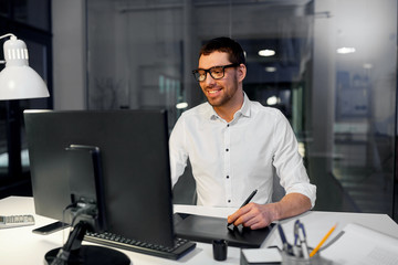 business, graphic design and technology concept - designer or businessman in glasses with computer and pen tablet working at dark night office